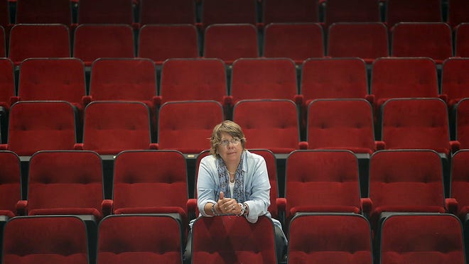 Zoe Bradford sits in the midst of empty chairs at the Company Theater in Norwell which she co-founded 41  years ago and which has been emptied the pandemic.