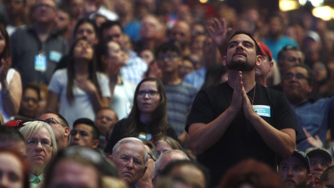 An attendee prays during Harvest America 2017. Taking place at University of Phoenix Stadium, the event has been billed "the nation’s largest one-day evangelistic outreach.” Attendance reached 38,000.