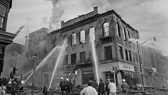In this July 15, 1967 file photo, firefighters direct streams of water onto a burning building at the corner of Prince and Court Streets in Newark, during a five-day span of deadly violence and looting.