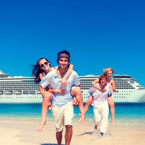 Two couples pose on a beach in front of a cruise s