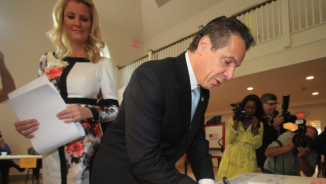 NY Gov. Andrew Cuomo signs in before voting in the Democratic primary with his girlfriend Sandra Lee at Mt. Kisco Presbyterian Church on Sept. 9, 2014