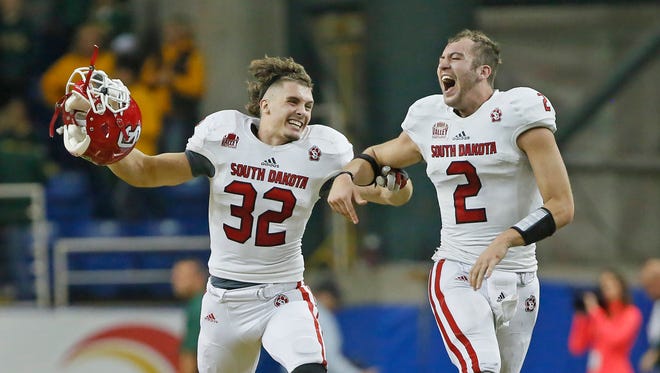 University of South Dakota's Jet Morland (32) and quarterback Ryan Saeger celebrate their 24-21 win over NDSU in October. The Coyotes' winning ways this year has earned the respect of their rivals in Brookings.