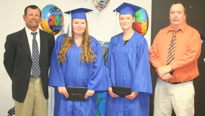 Lyon County School Board President Neal McIntyre, left, and school board member John Stevens, right, congratulate LCSD adult education graduates Tyerra Barnhardt, second from left, and Celina Zane at the June 2 ceremony at the adult education building in Fernley.