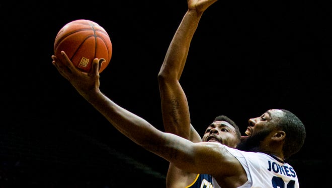Butler University forward Roosevelt Jones (21) takes the ball under the defense of University of Tennessee at Chattanooga forward Justin Tuoyo (5) who blocked the shot during first half action. Butler University hosted University of Tennessee at Chattanooga in an NCAA men's basketball game, Tuesday, Nov. 18, 2014.