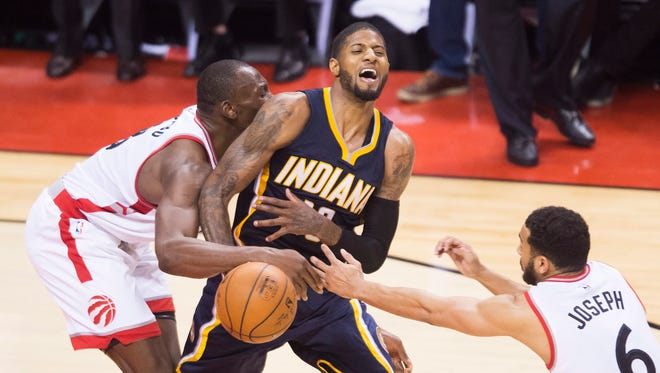 Indiana Pacers forward Paul George (13) gets fouled by Toronto Raptors centre Bismack Biyombo (8) as Raptors guard Cory Joseph (6) looks on during second half round one NBA playoff basketball action in Toronto on Sunday, May 1, 2016. (Nathan Denette/The Canadian Press via AP)