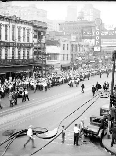 On the opposite side of the street, police and firefighters hold back the crowd at the fire on Michigan Avenue between First and Cass on July 28, 1931.