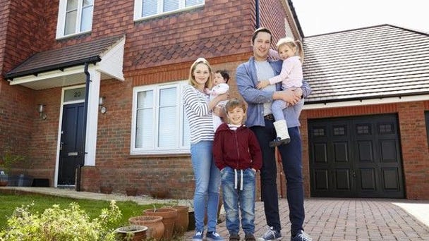 Young family standing in front of their home.