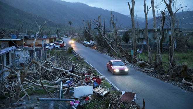 In this Sept. 26, 2017, file photo, neighbors sit on a couch outside their destroyed homes as sun sets in the aftermath of Hurricane Maria, in Yabucoa, Puerto Rico. U.S. government forecasters are expecting an active Atlantic hurricane season. The National Oceanic and Atmospheric Administration forecast released Thursday, May 24, 2018, calls for about 10 to 16 named storms, with about five to nine hurricanes.