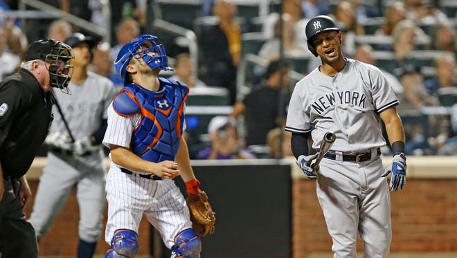 New York Mets catcher Travis d'Arnaud, center, looks up as Yankees Aaron Hicks (31) reacts after flying out in the seventh inning of an interleague baseball game against the New York Mets, Tuesday, Aug. 2, 2016, in New York. Home plate umpire Brian Gorman watches, far left.