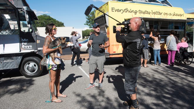 Kail Dudley and her dog, Feldspar, offers a critique of a food truck meal 
as "The Great Food Truck Race" films on Wednesday, May 24, 2017, in downtown Pensacola.