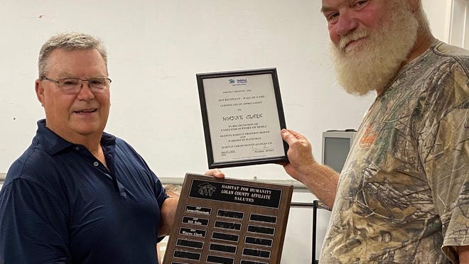 Outgoing president Bill Sahs, left, presents Wayne Clark with a certificate of appreciation Tuesday at the Habitat for Humanity Board meeting. Sahs holds the Wall of Fame plaque that will include Clark's name for 2019.