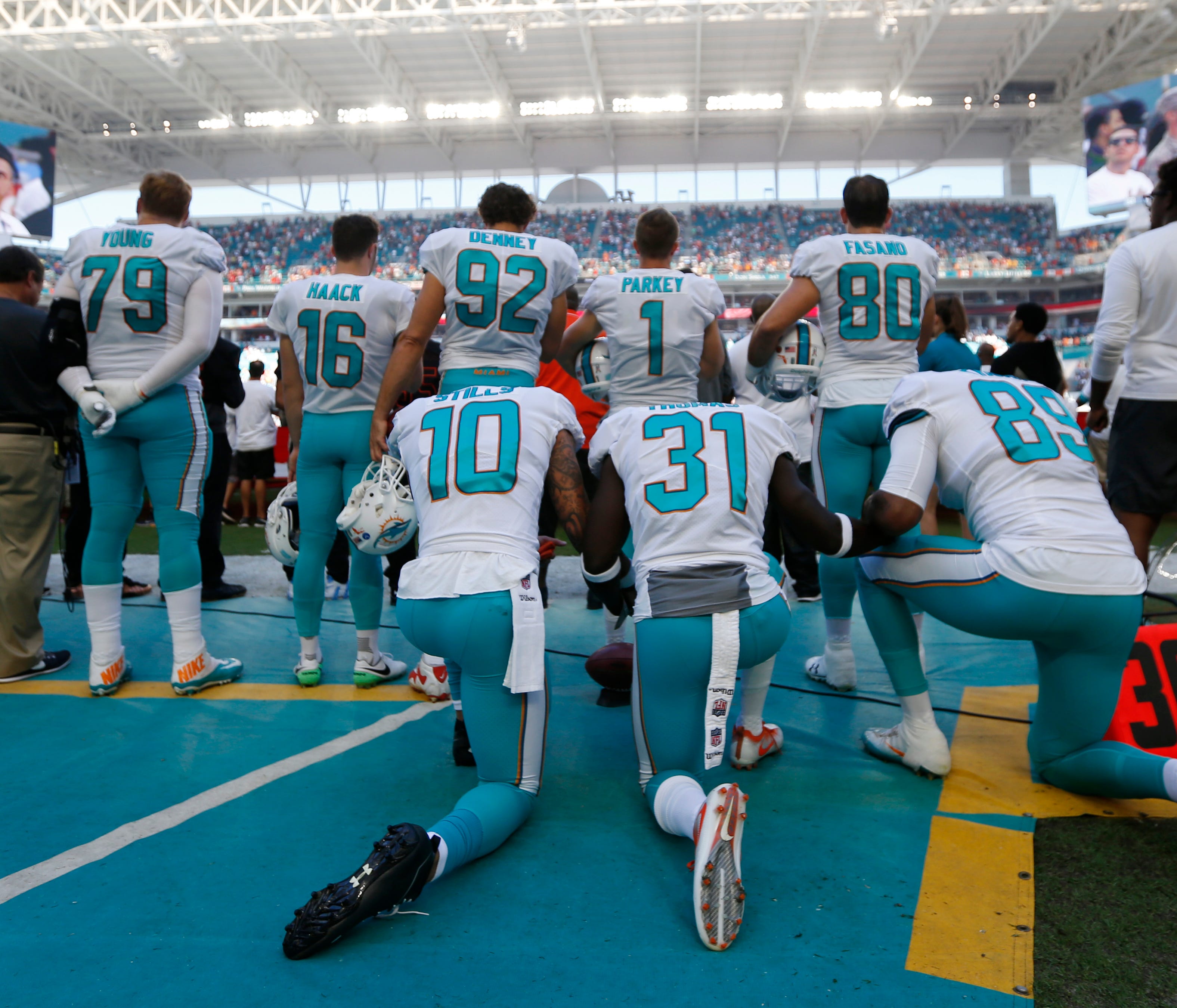 Miami Dolphins wide receiver Kenny Stills (10), free safety Michael Thomas (31) and tight end Julius Thomas (89), kneel during the National Anthem behind their teammates before an NFL football game against the Tampa Bay Buccaneers, Sunday, Nov. 19, 2