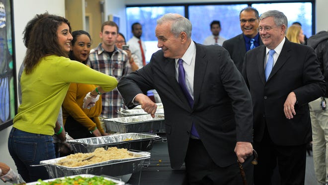 Gov. Mark Dayton, center, literally rubs elbows with students serving the food Saturday, April 2, at St. Cloud State University's Somali Night event as University President Earl H. Potter III looks on at right. Dayton spoke for the first time at an SCSU cultural night.