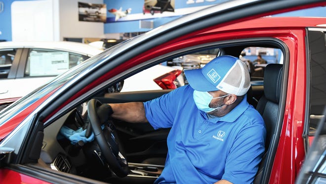 Rico Miller of Joe Machens Dealerships disinfects a floor model to keep customers safe.
