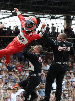 Helio Castroneves climbs the front stretch of fence with his teammates after winning the 2009 Indianapolis 500. Castroneves, a three-time winner, also won back-to-back races in 2001-02.