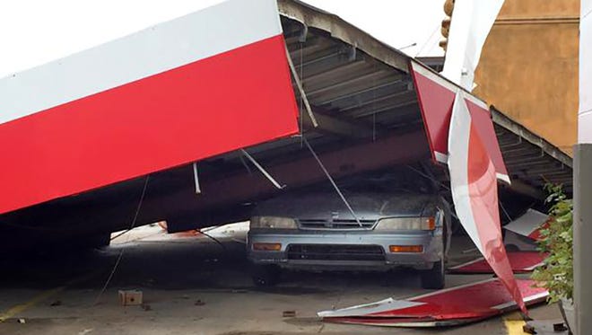A car is crushed by a portion of the building at an Exxon gas station in Madison, Miss.