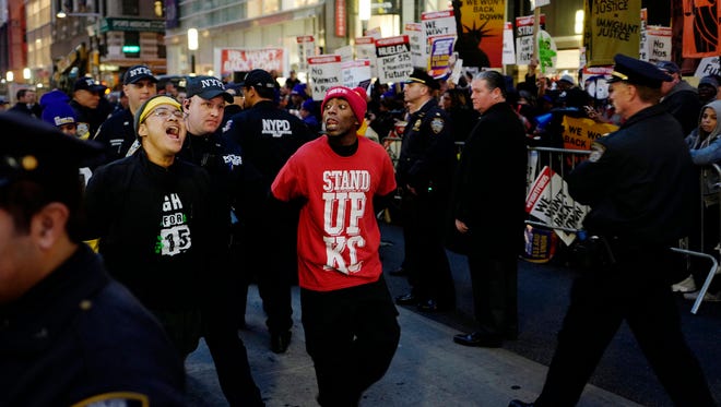 Two men, center, are arrested by police officers after blocking Broadway in front of a McDonald's restaurant, Tuesday, Nov. 29, 2016, in New York. About 25 chanting minimum-wage protesters were arrested. They were among about 350 people at a peaceful rally Tuesday. Protests were staged in numerous cities across the country.