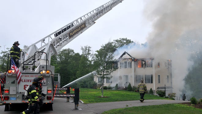 Firefighters work to extinguish flames after a small plane crashed into a house in Plainville, Mass., Sunday, June 28, 2015.