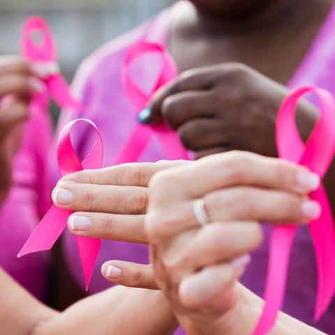 Medical workers hold pink breast cancer ribbons