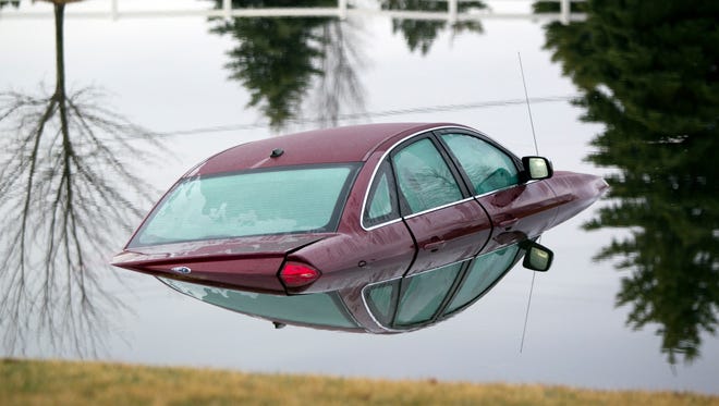 A car floats in a pond on 76th Street, Friday, April 3, 2015, in Caledonia Township, Mich.