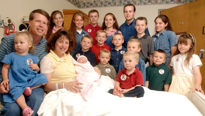 FILE - In this Aug. 2, 2007 file photo, Michelle Duggar, left, is surrounded by her children and husband Jim Bob, second from left, after the birth of her 17th child in Rogers, Ark.