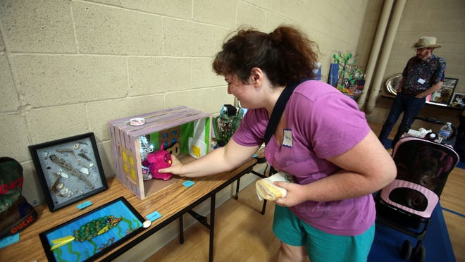 Christan Sears, of Thousand Palm, makes an adjustment to her diorama art piece during Mental Health Awareness Art Show on Tuesday at the Coachella Valley Rescue Mission in Indio.