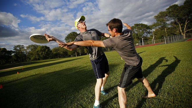 John Corfman, left, tries to throw past Tony Langel, as members of the Core House Church play ultimate Frisbee at Flora Park in Dubuque.