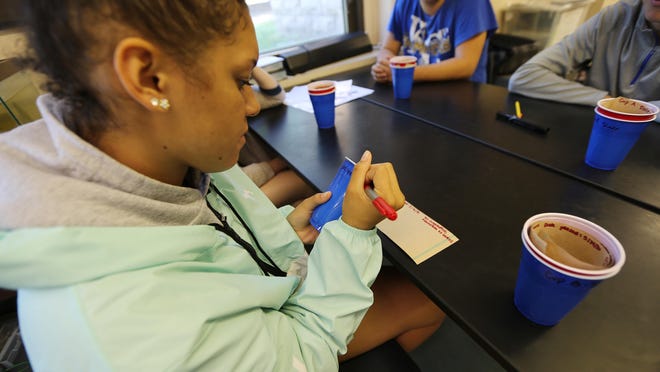 In this May 5, 2016 photo, student Chloe Colston, 15, labels a cup for mosquito larva collection at her school in Mahanttan, KS. The mosquitoes that can spread the disease Zika are already buzzing in places around the United States but the U.S. government could use a little help figuring out exactly where. The U.S. Department of Agriculture says high school students can do this important work using plastic cups and brown paper towels, mapping hotspots for mosquito controllers. (AP Photo/Josh Replogle)