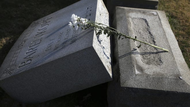 Flowers rest on a damaged headstone at Mount Carmel Cemetery Feb. 28, 2017 in Philadelphia. Scores of volunteers are expected to help in an organized effort to clean up and restore the Jewish cemetery where vandals damaged hundreds of headstones. (AP Photo/Jacqueline Larma)