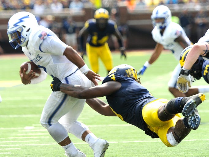 Michigan's Rashan Gary (3) holds on as he tackles Air