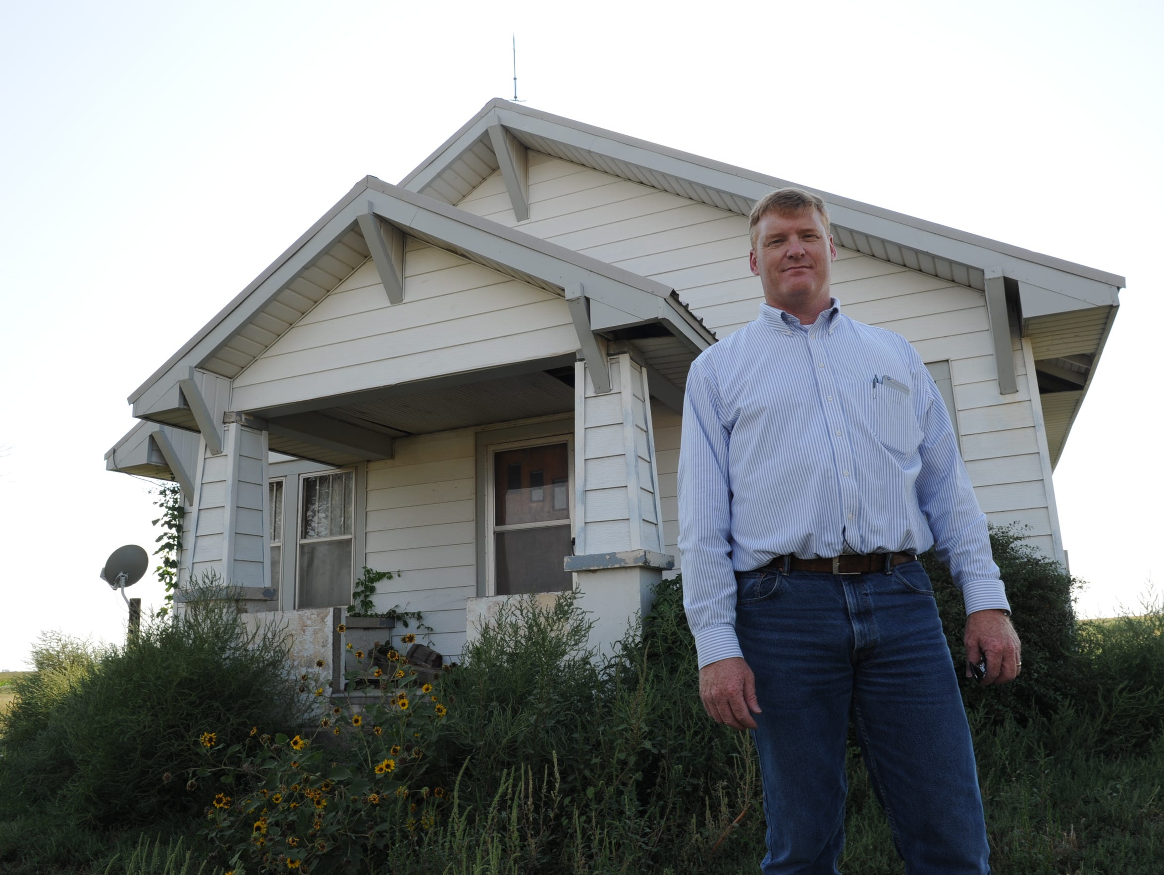 Jay Garetson stands in front of a farmhouse where he
