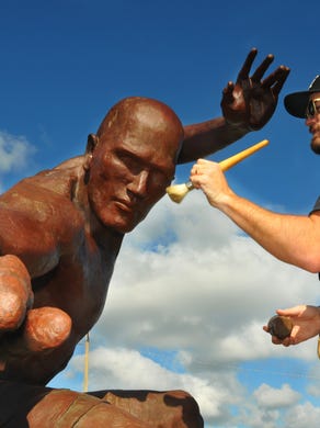 Chad Shores, the conservator and co-founder of Heritage Conservation, heats up the statue of Kelly Slater to apply a custom mix of wax to the metal. The weather, sun and salt affects the bronze in the statue, requiring conservation to the finish.