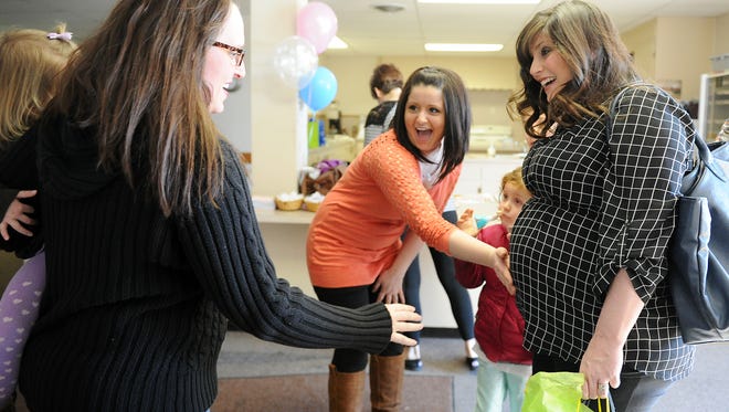 ERIN McCRACKEN / COURIER & PRESS" These are my babies," Sara McCarter (center) says as she introduces her sister-in-law, Tiffany Mundo, (left), to her babies and her surrogate Tara Pearce (right) at McCarter's baby shower at St.Vincent Catholic Church in Vincennes, Ind., on Feb. 7, 2015. The baby shower was the first time McCarter's family from Crown Pointe, Ind., met her surrogate. The McCarters are still somewhat in disbelief about the upcoming arrival of their biological twins. McCarter knew at a very young age she would only be able to have children through a surrogate and although her children will arrive in about 6 weeks she still feels like it is a dream.