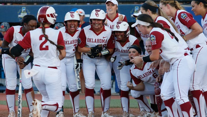 Oklahoma's Sydney Romero (2) is greeted at home plate by her teammates after hitting a home run against Auburn in the third inning of the first game of the best of the best of three  championship series during an NCAA college softball game in the NCAA Women's College World Series in Oklahoma City, Monday, June 6, 2016. (AP Photo/Sue Ogrocki)