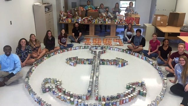 Assistant Principal James Sloan and teacher Julie Zielinski, sit alongside the Leadership students and over 1,600 food items the Westwood's Marine and Oceanographic Academy campus collected. All food will be donated to the Treasure Coast Food Bank