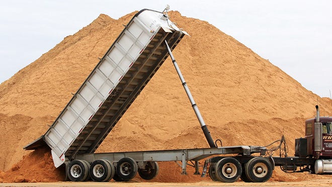 In this photo taken Feb. 13, 2012, a truck dumps a load of silica sand at Modern Transport Rail loading terminal in Winona, Minn. Winona County, Minnesota's only county to ban the mining of silica sand for use by the oil and gas industry in hydraulic fracturing, goes to court Thursday, May 10, 2018, to defend the ban.