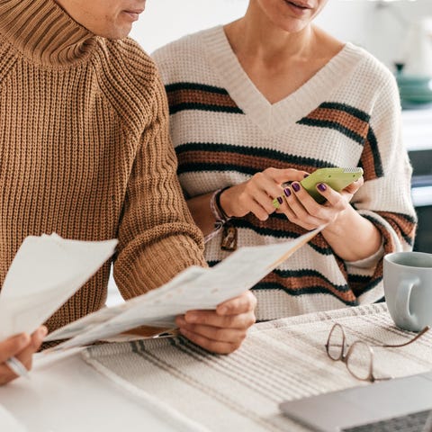 Two people sit at a desk with papers and a calcula