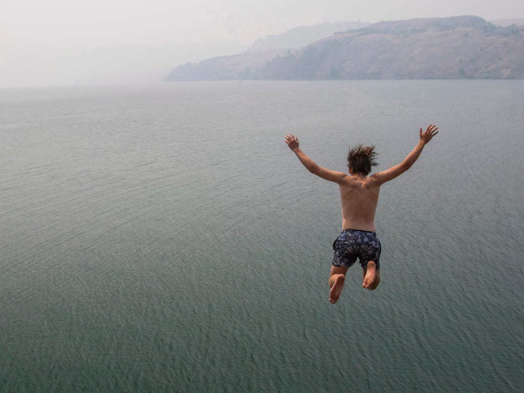Eli Garlick jumps into Lake Kalamalka in Vernon, British Columbia. The Okanagan area is blanketed with smoke from wildfires burning in the interior of the province.