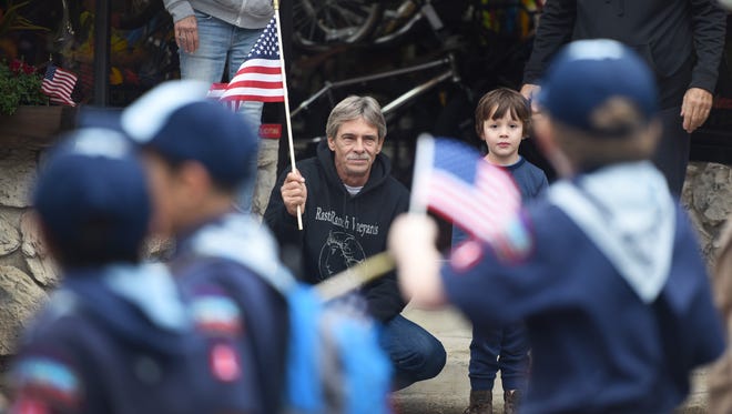 Jeff Kocsis waves a flag as he watches Clifton's Veterans Day Parade with his grandson Thomas on Sunday.