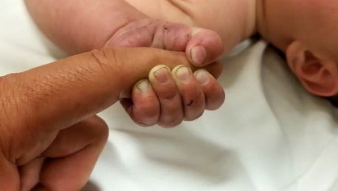 This Sunday, July 8, 2018 photo provided by the Missoula County Sheriff's Office shows a 5-month-old infant with dirt under their fingernails after authorities say the baby survived about nine hours being buried under sticks and debris in the woods. The Missoula County Sheriff's Office says the baby is in good condition at a hospital and calls it a "miracle" that the child survived the weekend ordeal. Authorities say they were called about a man threatening people in the Lolo Hot Springs area of western Montana's Lolo National Forest. Deputies apprehended the man who indicated that the baby was buried somewhere in the woods. (Missoula County Sheriff's Office via AP)