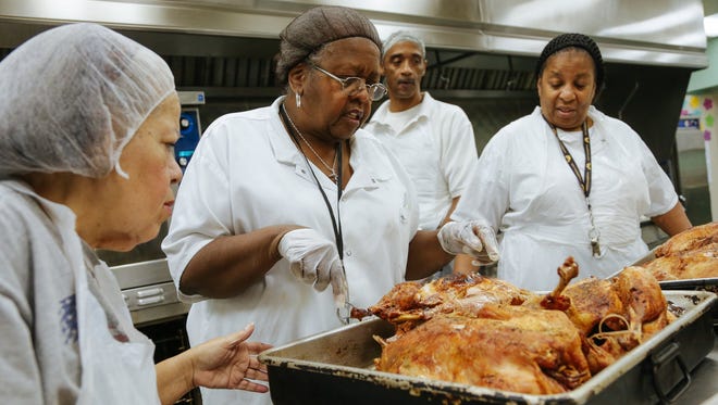 Hartford Memorial Baptist Church kitchen manager Vivian Scott, center, checks turkeys out of the oven with Janice Ashford, at left, Solomon Smith and Sharon Turner. The turkeys were prepared for Thanksgiving meals to be delivered to homeless people.