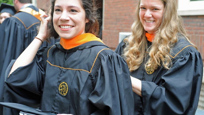 Catherine Lucero, left, is assisted by Julie Whitehead as the two prepare to receive their master's degree in Civil Engineering Saturday during Purdue's 225th commencement exercise. Findings from the Gallup-Purdue Index released Tuesday found nearly half of college graduates have delayed postgraduate education due to their student loans.