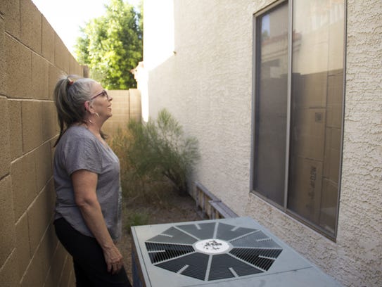 J. Lily Keohane, 64, next to her broken AC unit, examines