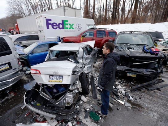 A man inspects vehicles piled up in an accident on Feb. 14, 2014, in Bensalem, Pa.