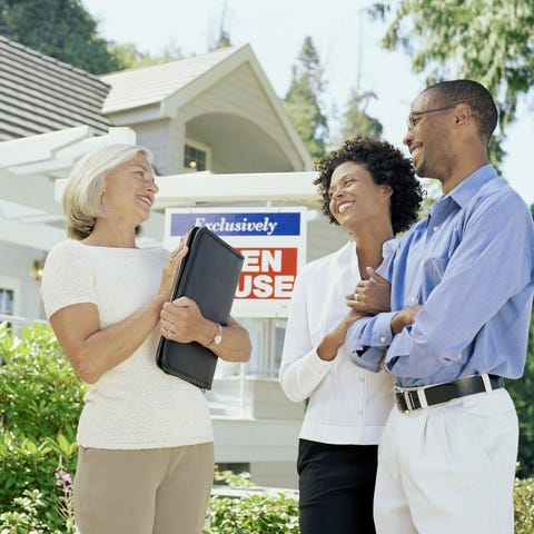 A real estate broker and a couple stand in front o