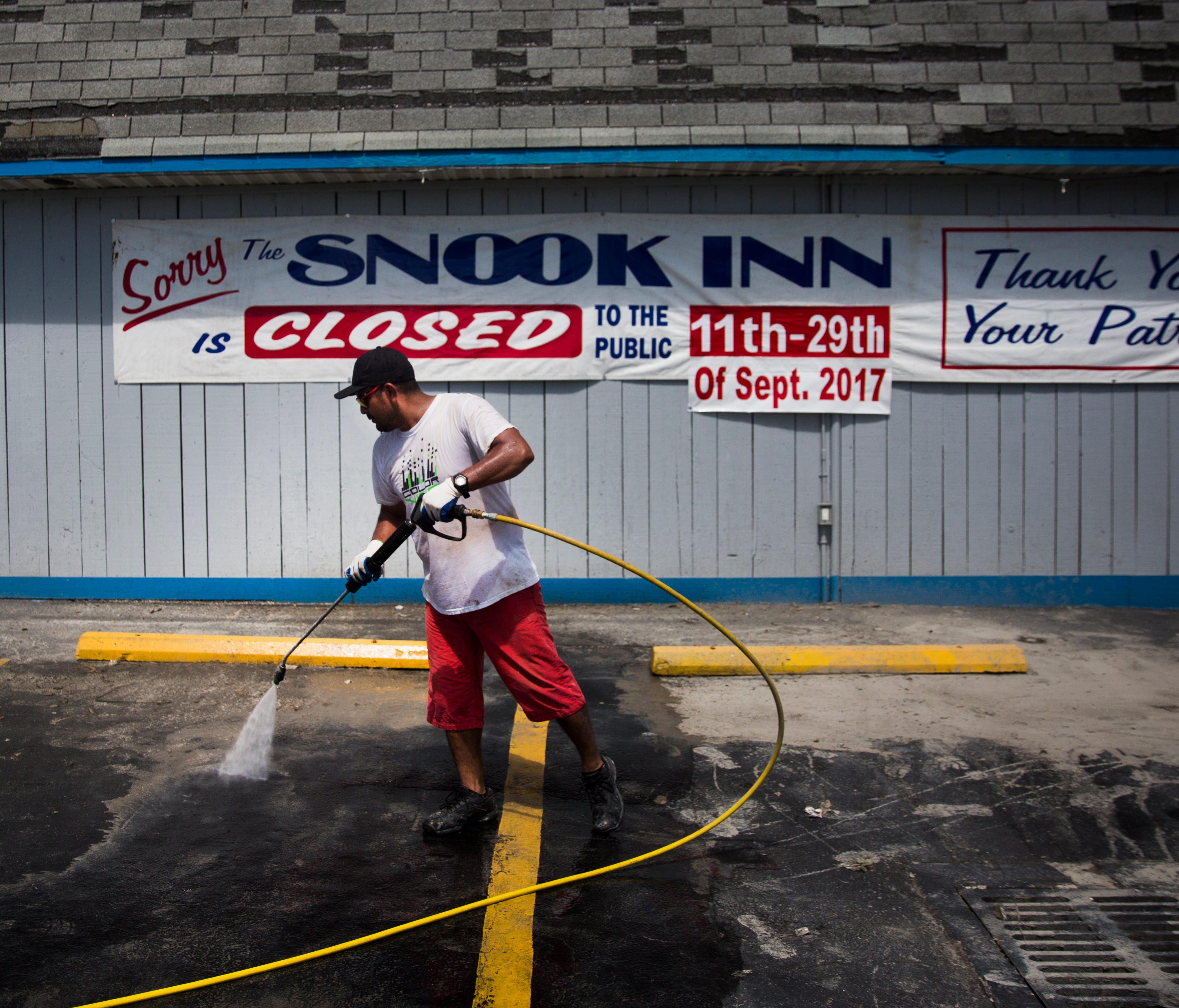 Roberto Valesquez pressure washes the parking lot at the Snook Inn on Marco Island, Fla. after Hurricane Irma.