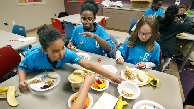Soleil Disalvo, 7, Elise Smith, 9, and Kirsten Griffith, 11, dip bananas in yogurt and add cereal amongst other things while making healthy snacks at the David F. Gantt Recreation Center.
