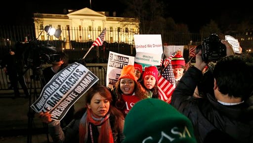 In this Nov. 20, 2014 file photo, people chant during a demonstration in front of the White House in Washington as President Barack Obama announced executive actions on immigration during a nationally televised address. The US judge assigned to rule in the lawsuit over President Barack Obama's changes to immigration rules last year accused the Obama administration of participating in criminal conspiracies to smuggle children into the country by reuniting them with parents living here illegally.