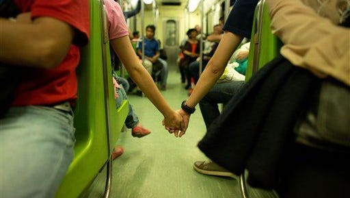 A Young Couple Unable To Find Seats Together In The Metro Hold Hands