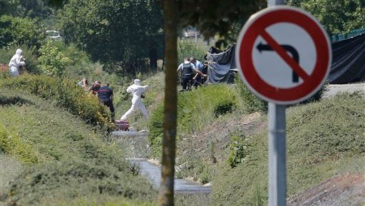 Investigating police officers work outside the plant where an attack took place, Friday, June 26, 2015 in Saint-Quentin-Fallavier, southeast of Lyon, France. French authorities say one person has been beheaded in an attack and explosion at a gas factory in the southeastern part of the country. Officials say banners with Arabic writing were found near the body. Authorities have opened a terrorism investigation. (AP Photo/Laurent Cipriani)
